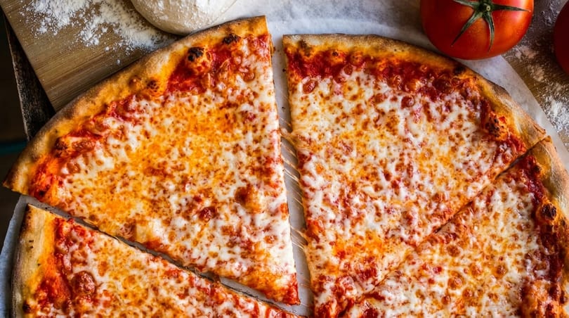 Close-up of a cheese pizza with several slices pulled apart, showing melted cheese strings.